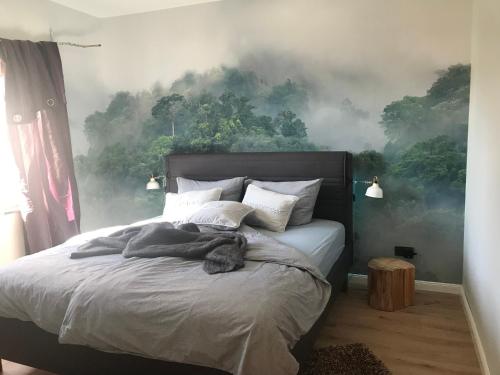 - une chambre avec un lit orné d'une fresque murale représentant la forêt dans l'établissement Ferienwohnung Piesbach, à Nalbach