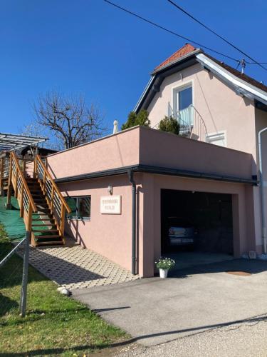 ein rosafarbenes Haus mit einer Garage und einer Treppe in der Unterkunft Ferienwohnung Pichler in Feistritz im Rosental