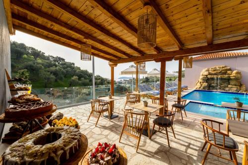 un patio con piscina, tavoli e sedie di Skiathos Avaton Suites & Villas, Philian Hotels and Resorts a Megali Ammos