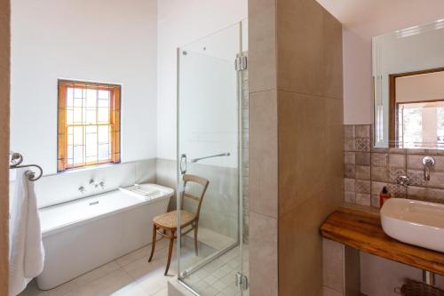 een badkamer met een bad, een wastafel en een douche bij 06 On Burger in De Rust