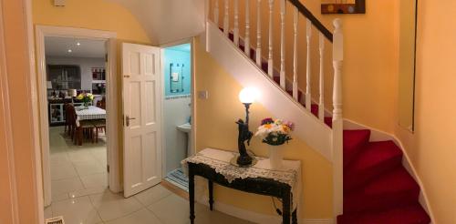 a hallway with a staircase with a vase of flowers on a table at Seascape on the edge of town: 4 beds all ensuite. in Belmullet