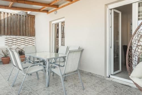 a glass table and chairs on a patio at Alpha & Omega in Karpathos Town