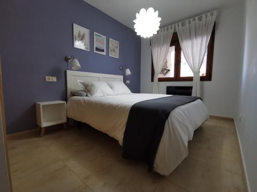 ein Schlafzimmer mit einem großen Bett mit blauer Wand in der Unterkunft Precioso apartamento en la playa de la Lanzada. in Sanxenxo