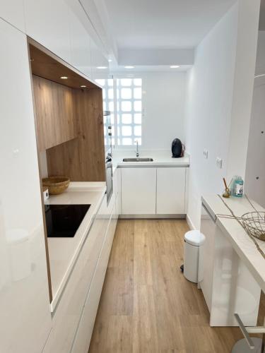 a kitchen with white cabinets and a wooden floor at Casa del olivo in Almuñécar