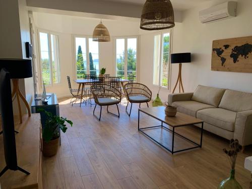 ein Wohnzimmer mit einem Sofa, einem Tisch und Stühlen in der Unterkunft Le Rossignol 1, Aiguebelle plage in Le Lavandou