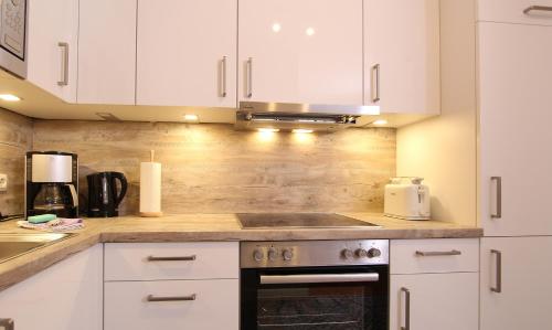 a kitchen with white cabinets and a stove top oven at Ferienwohnung Ines in Kühlungsborn