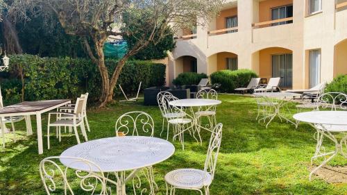 un groupe de tables et de chaises dans une cour dans l'établissement Le Floréal, à Vence