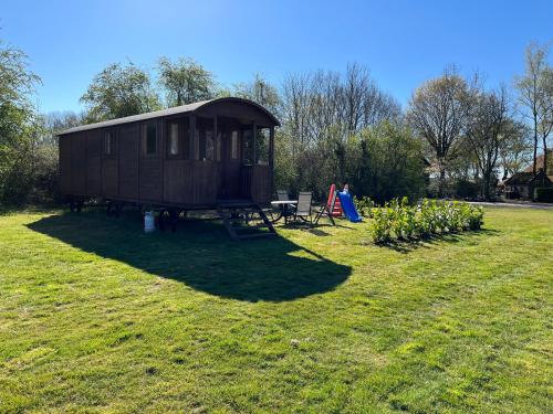 a small cabin in the middle of a grass field at Pipowagen voor 4 personen in Diever