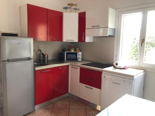 a kitchen with red cabinets and a white refrigerator at Appartamenti Sterlizia 2 in Lacona