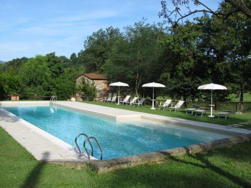 a swimming pool with chairs and umbrellas in a yard at Antico Borgo La Torre Agriturismo in Reggello