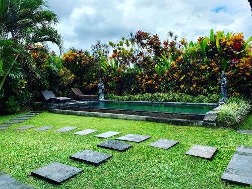 a swimming pool in a garden with grass and trees at Pondok Naya - CHSE Certified in Ubud