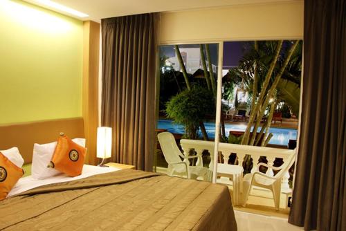 a bedroom with a bed with a view of a balcony at Windmill Resort Hotel Pattaya in North Pattaya