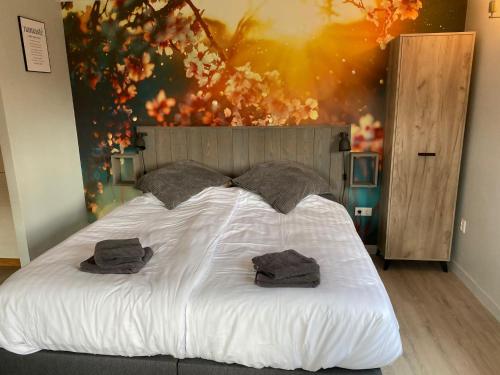 a bedroom with a large bed with two towels on it at De Veluwse bos Lodge in Otterlo
