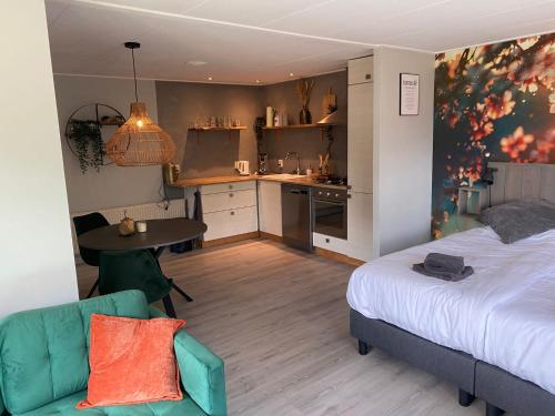 a bedroom with a bed and a table and a kitchen at De Veluwse bos Lodge in Otterlo