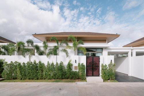 ein weißes Haus mit einem Zaun und Palmen in der Unterkunft Villa Alanna Phuket in Strand Bang Tao
