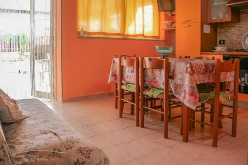 a kitchen with orange walls and a table and chairs at Apartment Timpirussimare in Sciacca