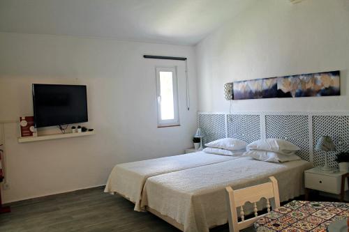 een slaapkamer met een bed en een flatscreen-tv bij Óasis - Pedras D' El Rei T0 in Santa Luzia