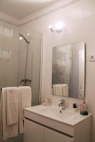 a white bathroom with a sink and a mirror at Óasis - Pedras D' El Rei T0 in Santa Luzia