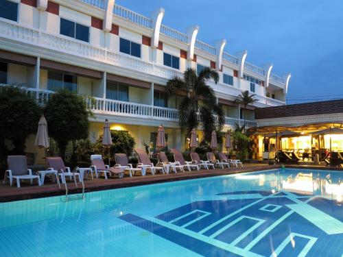 a hotel swimming pool with chairs and a building at Windmill Resort Hotel Pattaya in Pattaya North