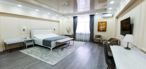 a bedroom with a bed and a table and a desk at Grand Holiday Hall in Pavlodar