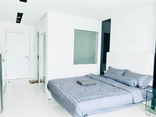 - un grand lit dans une chambre blanche avec une photo sur le mur dans l'établissement City Center Residence Condominium Pattaya RJ, à Pattaya