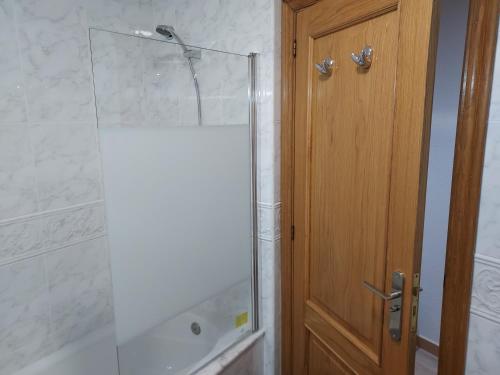 uma casa de banho com um chuveiro e uma porta de madeira em Apartamento Calzada Romana em Lugo