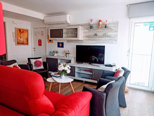 sala de estar con muebles de color rojo y TV en La Mamma Mía, en Benidorm