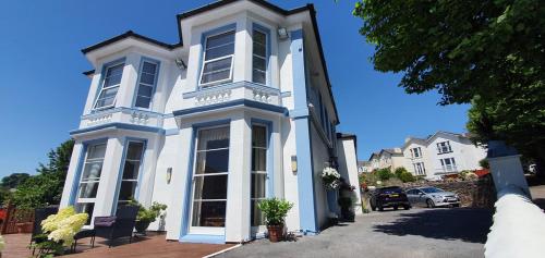 a white house with large windows on a street at Tor Dean Guest House in Torquay