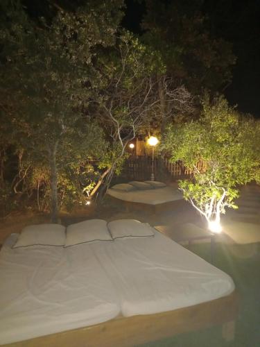 a large white bed with two pillows on it at night at Camping U STABIACCIU in Porto-Vecchio