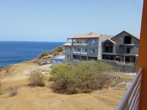 a house on the side of a hill next to the ocean at chez albino guest house in São Filipe