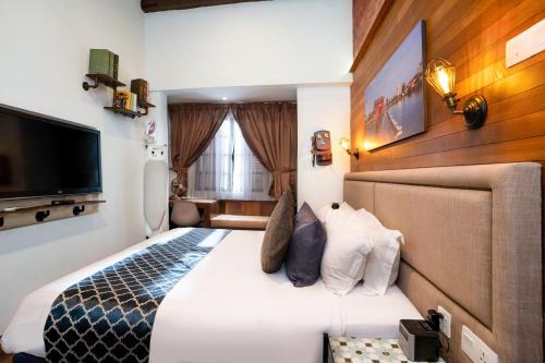 une chambre d'hôtel avec un lit et une télévision dans l'établissement RARE Heritage House, à George Town