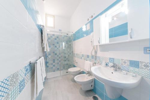 baño azul y blanco con lavabo y aseo en Hotel Celeste, en Procida