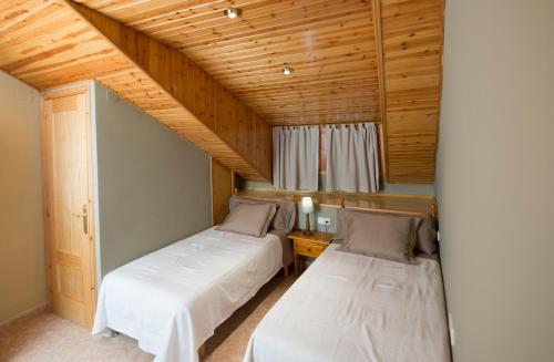 zwei Betten in einem Zimmer mit Holzdecken in der Unterkunft Casa Apartamento de montaña in Espúy