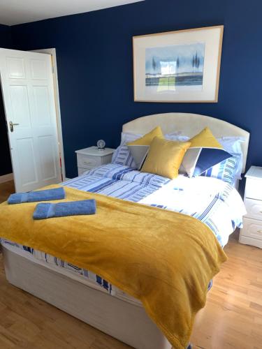a bedroom with a bed with a yellow blanket on it at Seascape on the edge of town: 4 beds all ensuite. in Belmullet