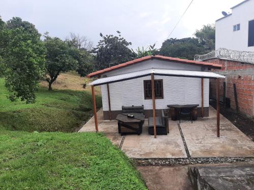 a small white shed with a table and a patio at Casita familiar de campo condina in Pereira