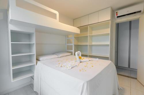 Schlafzimmer mit einem weißen Bett und weißen Regalen in der Unterkunft Muro Alto Condomínio Clube - FLAT TÉRREO in Porto De Galinhas