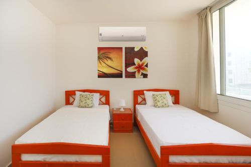 two twin beds in a room with a window at Prime Holidays Seashell in El Alamein