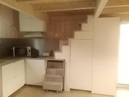 a kitchen with white cabinets and stairs in a room at Studio dans les pins Lacanau in Lacanau