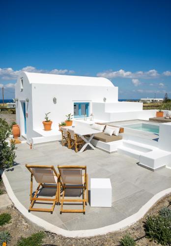 a patio with chairs and a table and a house at Vino Houses Santorini in Oia