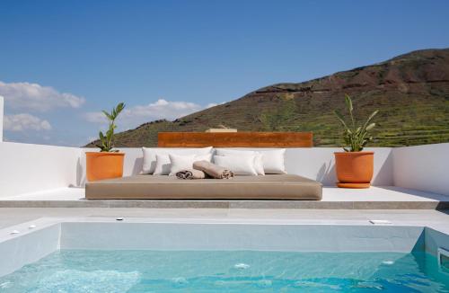 a bed sitting on a ledge next to a swimming pool at Vino Houses in Oia