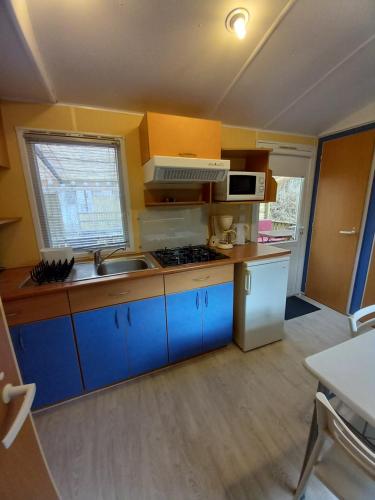 a small kitchen with blue cabinets and a sink at Camping du Moulin de Thoard in Thoard