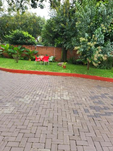 a patio with a red table and chairs in a yard at G On M Guest House in Pretoria