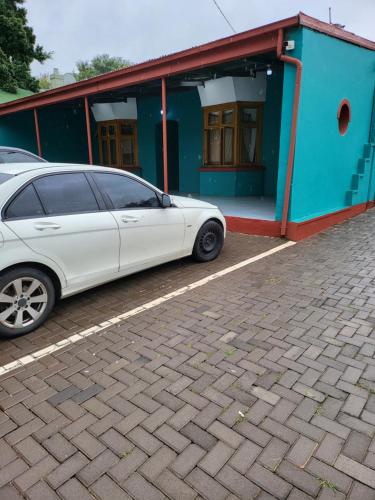 a white car parked in front of a blue building at G On M Guest House in Pretoria