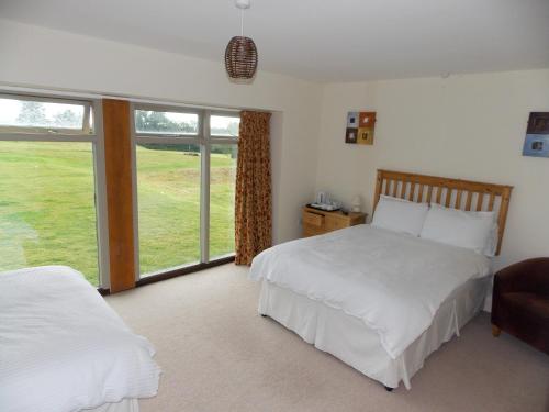 a bedroom with two beds and a large window at Canons Court Mews in Wotton under Edge