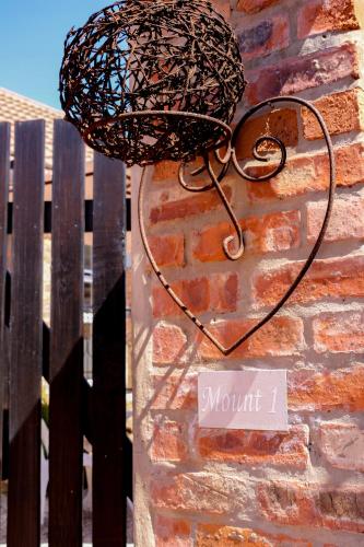 a heart shaped sign with a hat on a brick wall at Seeplaas Guesthouse in Groot Brak Rivier