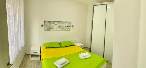 una piccola camera da letto con un letto giallo con lenzuola verdi di Makera a Tivat
