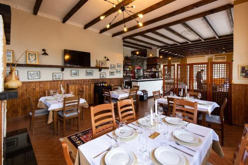 une salle à manger avec des tables et des chaises blanches dans l'établissement Rozmarine, à Pëllumbas