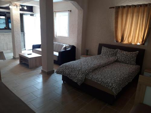 een slaapkamer met een bed, een stoel en een bank bij Kazablanka Rooms Aerodrom in Podgorica