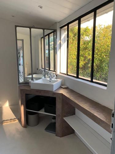 une salle de bain avec un lavabo et un grand miroir dans l'établissement Beach Cottage, au Bois-Plage-en-Ré