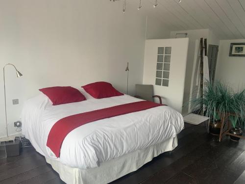 a bedroom with a large bed with red pillows at Beach Cottage in Le Bois-Plage-en-Ré